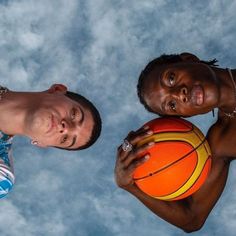 two men standing next to each other with a basketball in their hands, looking up at the camera