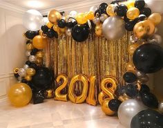 balloons and streamers decorate the entrance to a new year's eve party in gold, black and silver