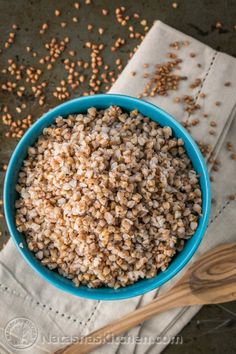 a blue bowl filled with brown seeds next to a wooden spoon on top of a napkin