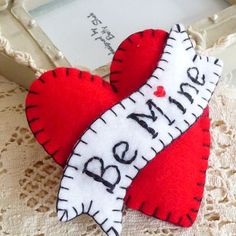 a red and white heart shaped brooch sitting on top of a lace doily