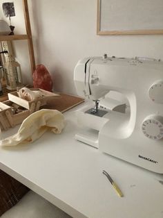 a white sewing machine sitting on top of a table next to a piece of cloth