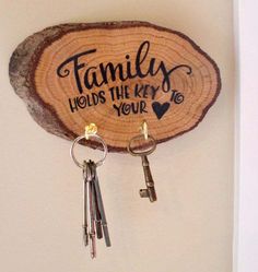 a wood slice with two keys hanging from it's sides and the words family holds the key to your heart