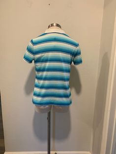 This is a nice vintage polo shirt. There are no tags or label. It measures like a small men's or a women's medium. Turquoise and white stripes with a white collar. There are two Metal Snaps for closure. It has a very small mark as shown in last photo, otherwise in great condition. I will be mailing this Priority Mail and First Class International. Measurements Bust or Chest ~ 36 Inch Waist ~ 34 Inch Shoulder to Shoulder ~ 15 Inch Length ~ 24 Inch Blue Fitted Top With Collared Neckline, Casual Blue Top With Collared Neckline, Blue Cotton Tops With Collared Neckline, Casual Blue Tops With Collared Neckline, Fitted Light Blue Polo Shirt With Polo Collar, Light Blue Fitted Polo Shirt With Polo Collar, Blue Cotton Top With Collared Neckline, Blue Fitted Collared T-shirt, Blue Retro Collared Tops