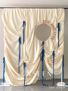 a white curtain with blue ribbons around it and a mirror on the wall behind it