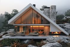 a modern house on the top of a mountain with rocks and trees around it, lit up at night