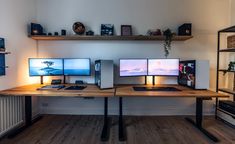 three computer monitors sitting on top of a wooden desk