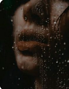 a woman's face is seen through the raindrops on a glass window