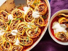 an oval casserole dish filled with pasta and meat, garnished with sour cream