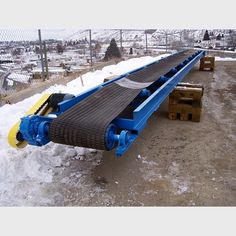 a blue conveyor belt sitting on top of snow covered ground