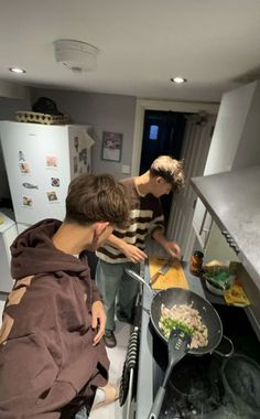 two young men are cooking in the kitchen