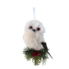 an owl ornament hanging from a tree branch with red berries and pine needles