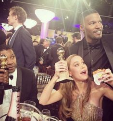 two people sitting at a table with food and drinks in front of them, one holding an award