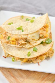 three tortillas stacked on top of each other with green onions and shredded cheese