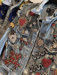 denim jacket with embroidered patches and beads on display at a clothing store in the city