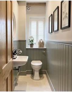 a white toilet sitting under a window next to a sink and a mirror in a bathroom