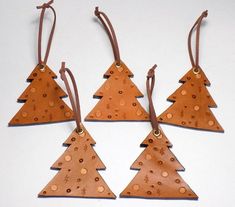 four pieces of leather with holes on them are hanging from brown cords and decorated with gold dots