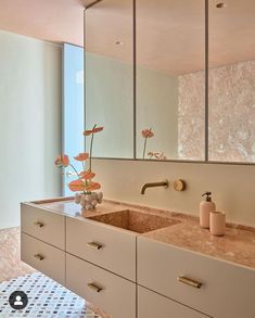 a bathroom with two sinks, mirrors and flowers in vases on the counter top