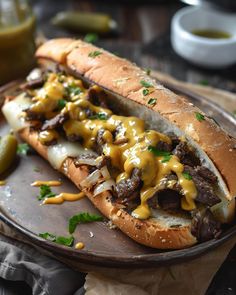 a steak sandwich with cheese and pickles on a wooden platter next to mustard