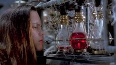 a woman looking at some bottles with liquid in them on a shelf next to wires