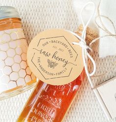 two jars of honey sitting on top of a table next to a bottle of honey