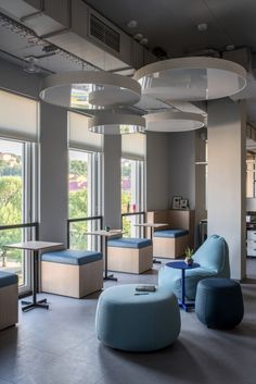 an office lobby with blue chairs and round lights hanging from the ceiling, along with large windows