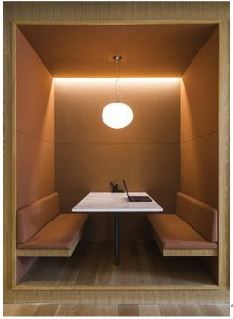 an empty room with two benches and a table in the corner, all lit up by a round light fixture