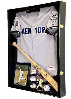 a new york yankees baseball uniform and bat in a display case with an autographed photo