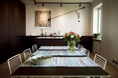 a dining room table is set with plates and flowers in a vase on the table