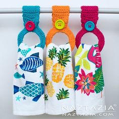 three hand towels hanging on a clothes line with colorful fish and pineapples printed on them