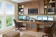 a home office with two computer screens on the wall and chairs in front of it