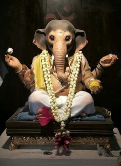 an elephant statue sitting on top of a table with beads around it's neck