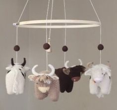 several knitted animals hanging from a white circular mobile with black and brown balls on it