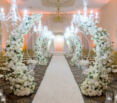 the aisle is decorated with white flowers and chandeliers for an elegant wedding ceremony