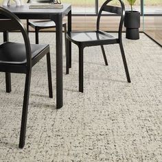 two black chairs sitting on top of a carpeted floor next to a table with a potted plant