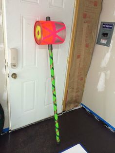 a paper mache on the floor in front of a white door with a green and red handle