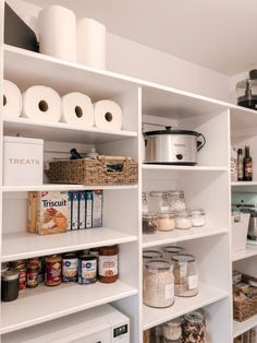 an organized pantry with white shelving and lots of food on the shelves, including rolls of toilet paper