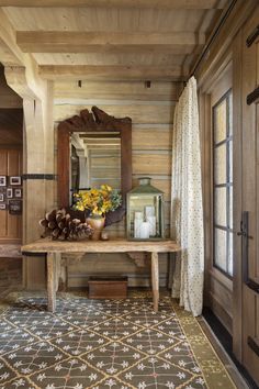 a wooden table sitting in the middle of a room next to a mirror and door