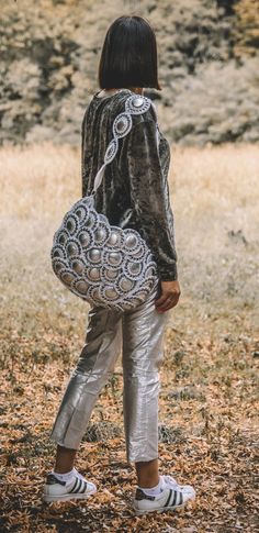 a woman standing in the grass holding a purse