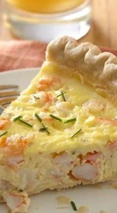 a piece of quiche on a plate with a fork and glass in the background