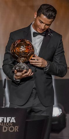 a man in a tuxedo holding a ballon d'or trophy