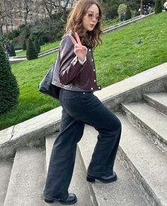 a woman standing on some steps giving the peace sign