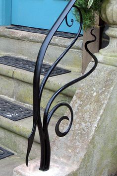 an iron stair rail on the steps leading up to a blue door