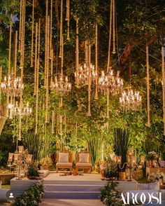 an outdoor ceremony with chandeliers and greenery hanging from the ceiling at night