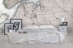 there is a bed with white sheets and pillows on the floor in front of a map