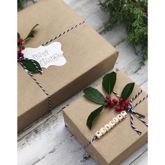 two presents wrapped in brown paper and decorated with holly leaves, berries and twine