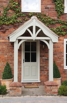 a white door and window in front of a brick building with ivy growing on it