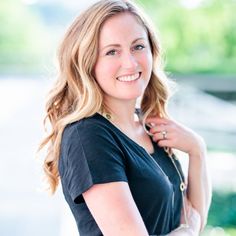 a woman with blonde hair is smiling and wearing a black shirt, jeans and heels