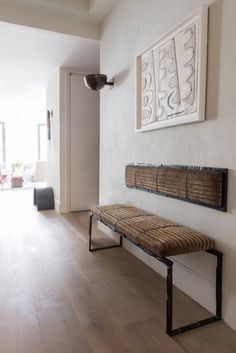 a wooden bench sitting on top of a hard wood floor next to a white wall