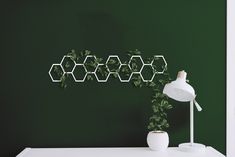 a white table topped with a lamp next to a wall mounted hexagonals