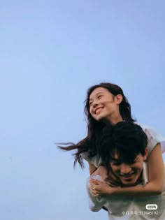 a man carrying a woman on his back while flying a kite in the sky behind him